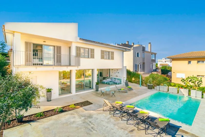 Una casa moderna da a una piscina exterior y una zona de estar en el patio.