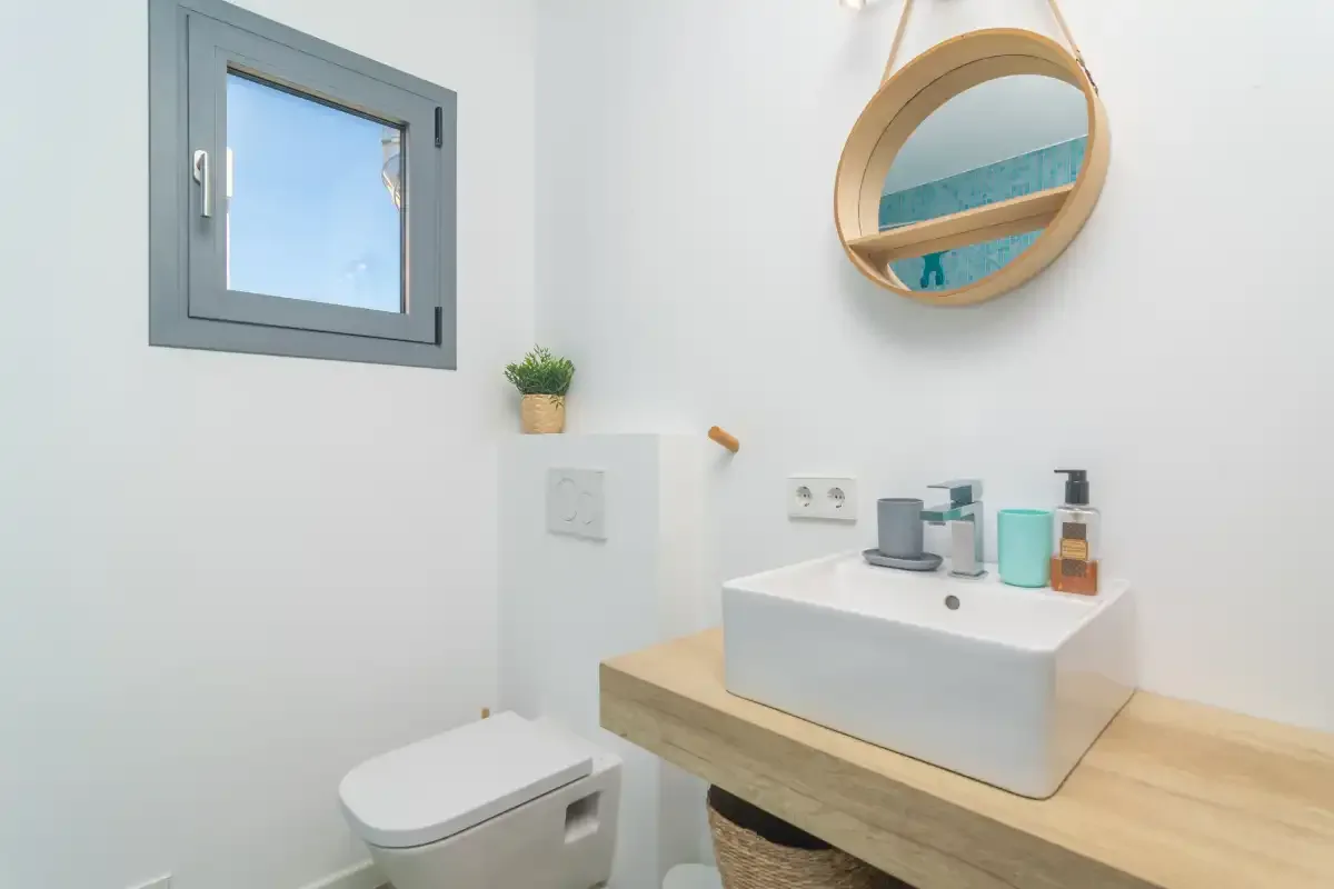 Un baño luminoso con un lavabo sobre encimera y una ventana pequeña.
