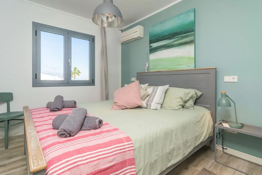 Un dormitorio con una cama, una manta a rayas y una ventana.