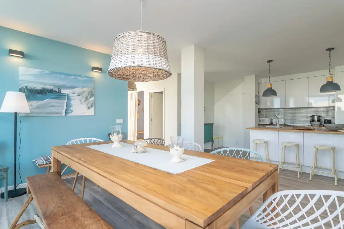 Comedor abierto con una mesa de madera junto a una cocina luminosa.