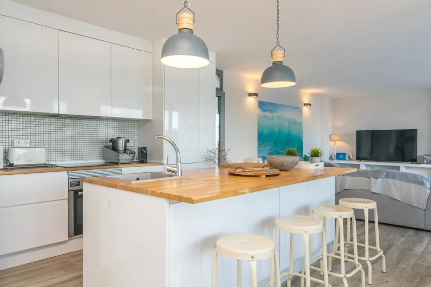 Una luminosa cocina abierta al salón, con una isla de encimera de madera.