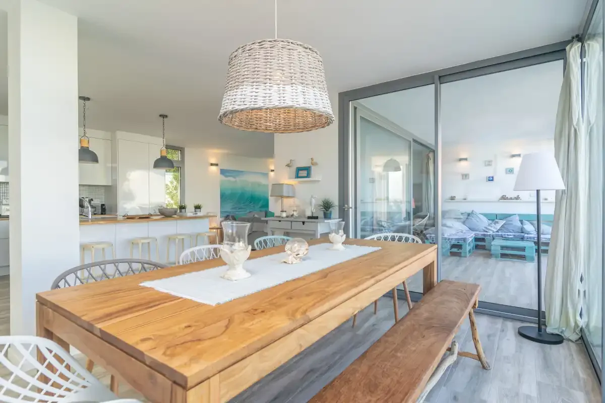 Comedor con una mesa de madera junto a una cocina abierta y luminosa.