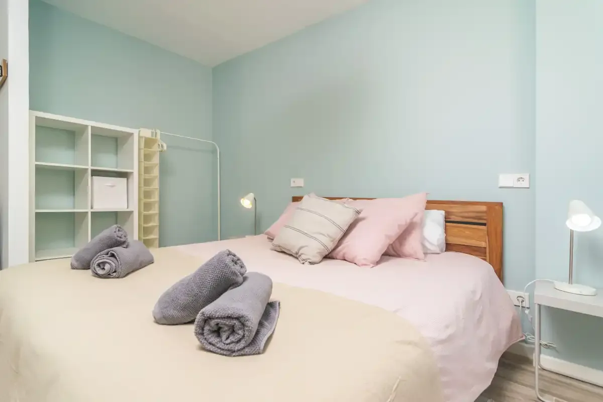 Un dormitorio con dos camas, ropa de cama rosa y toallas.