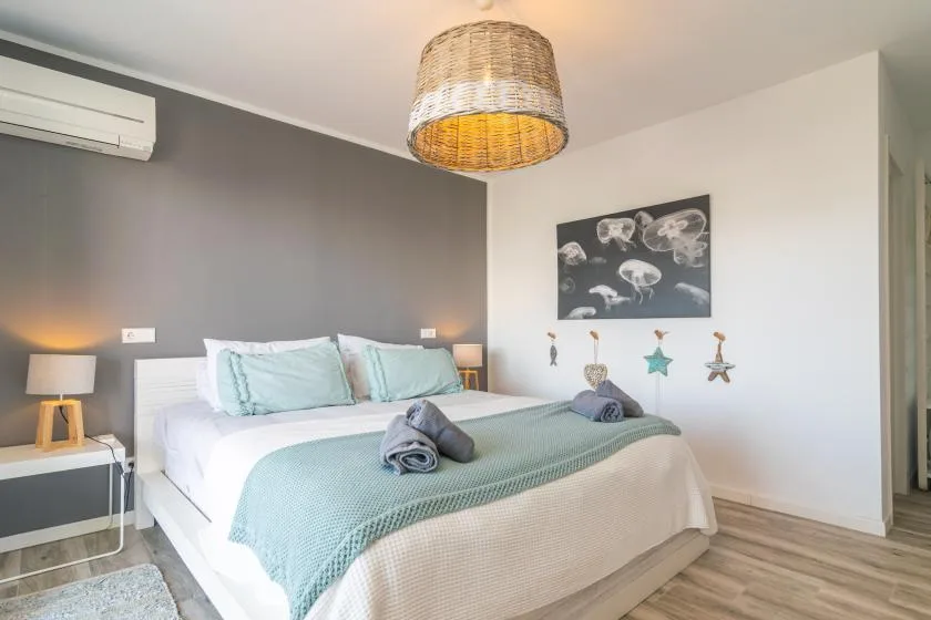 Un dormitorio con una cama bien tendida y cuadros en la pared.