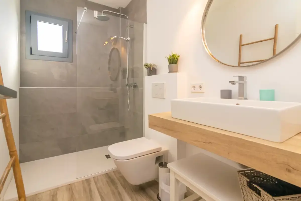 Un baño moderno con ducha de vidrio, inodoro suspendido y lavabo sobre encimera.