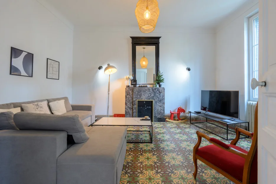 A bright living room with a gray seating area, fireplace, and television.