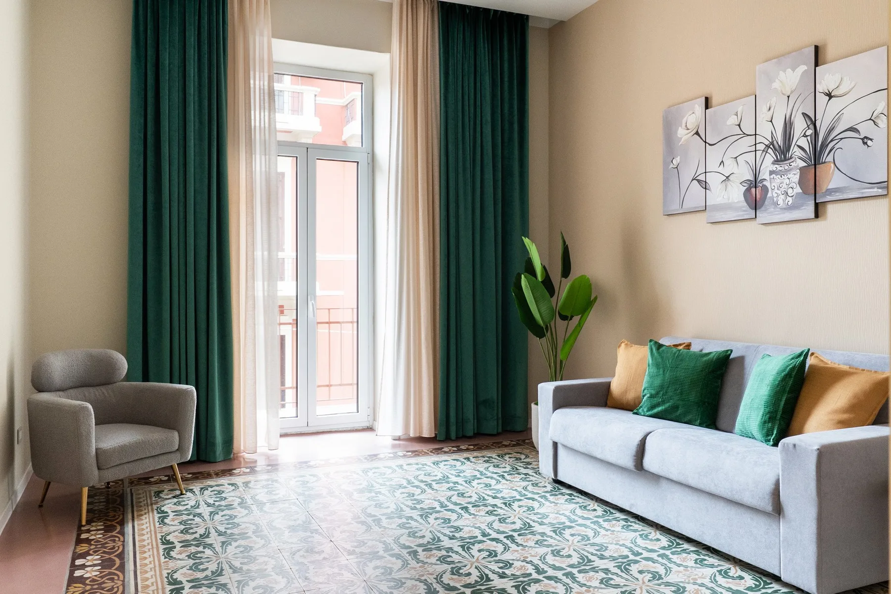 A living room with seating, tall curtained windows, and a patterned rug.