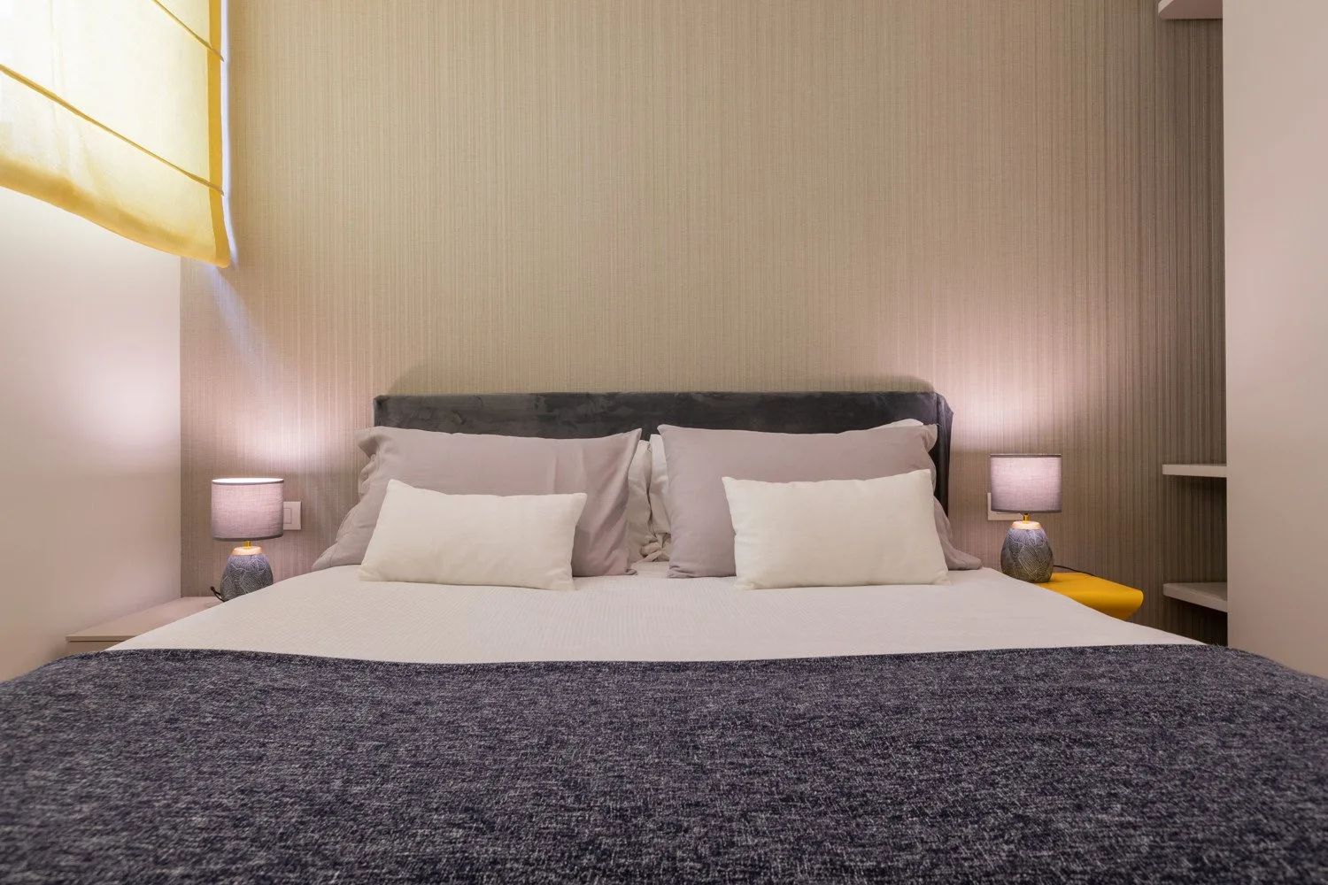 Un dormitorio con una cama bien hecha y lámparas a ambos lados.