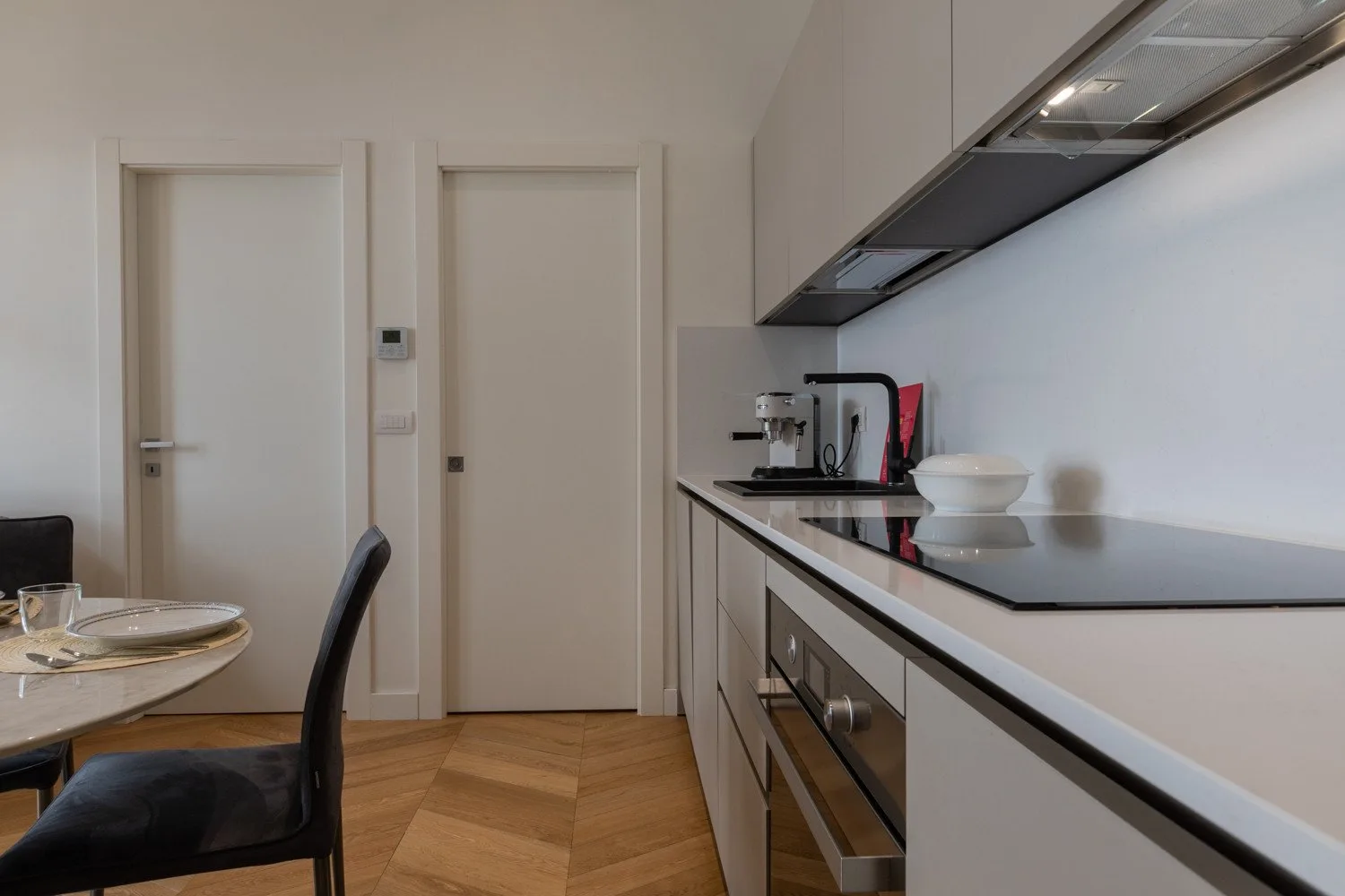 Una cocina moderna con una encimera larga, pequeños electrodomésticos y una mesa de comedor.
