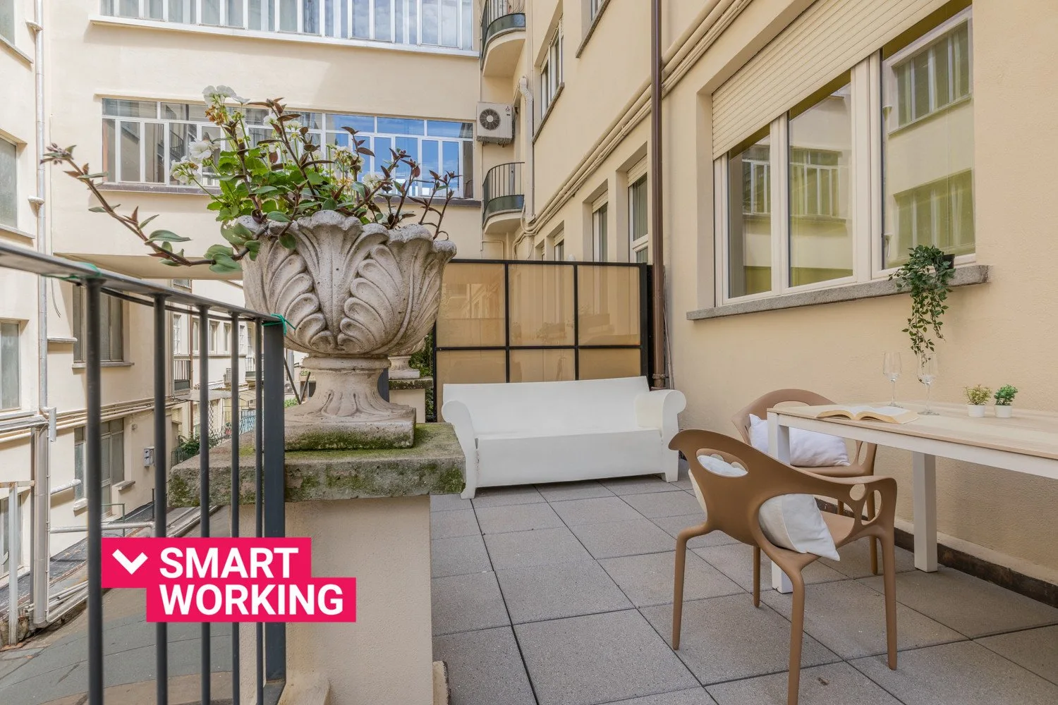 Una terraza en un patio con asientos al aire libre y una gran jardinera.