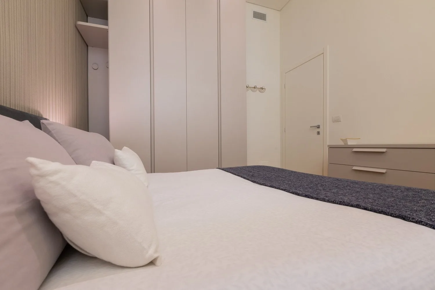 Un dormitorio con una cama bien tendida y armarios empotrados.