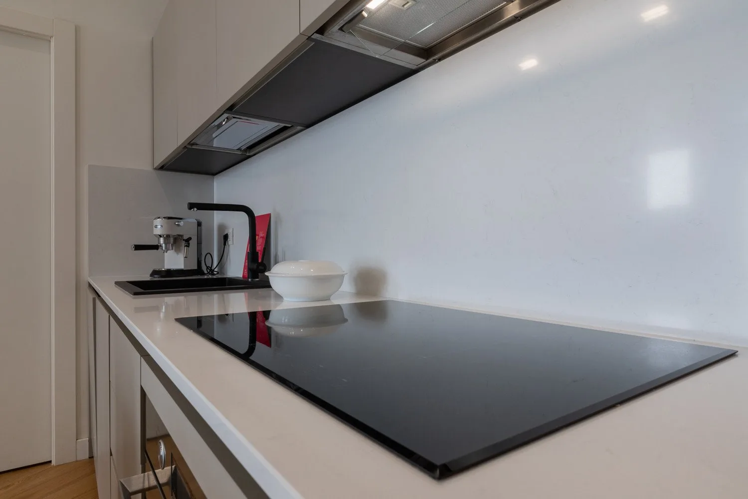 Una encimera de cocina moderna con una placa negra y pequeños electrodomésticos.