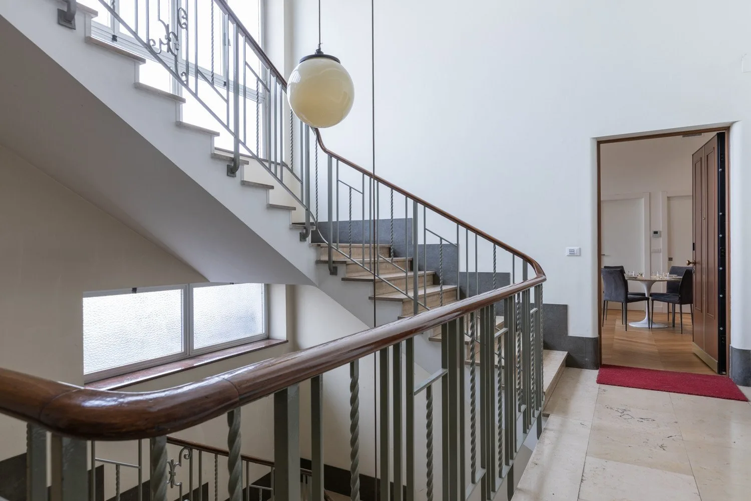 Un pasillo interior con una escalera y una puerta que da a otra habitación.