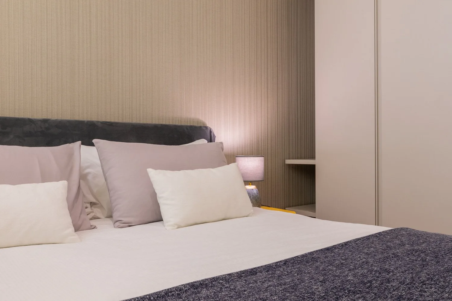 Un dormitorio con una cama tendida y una lámpara junto a la cama.