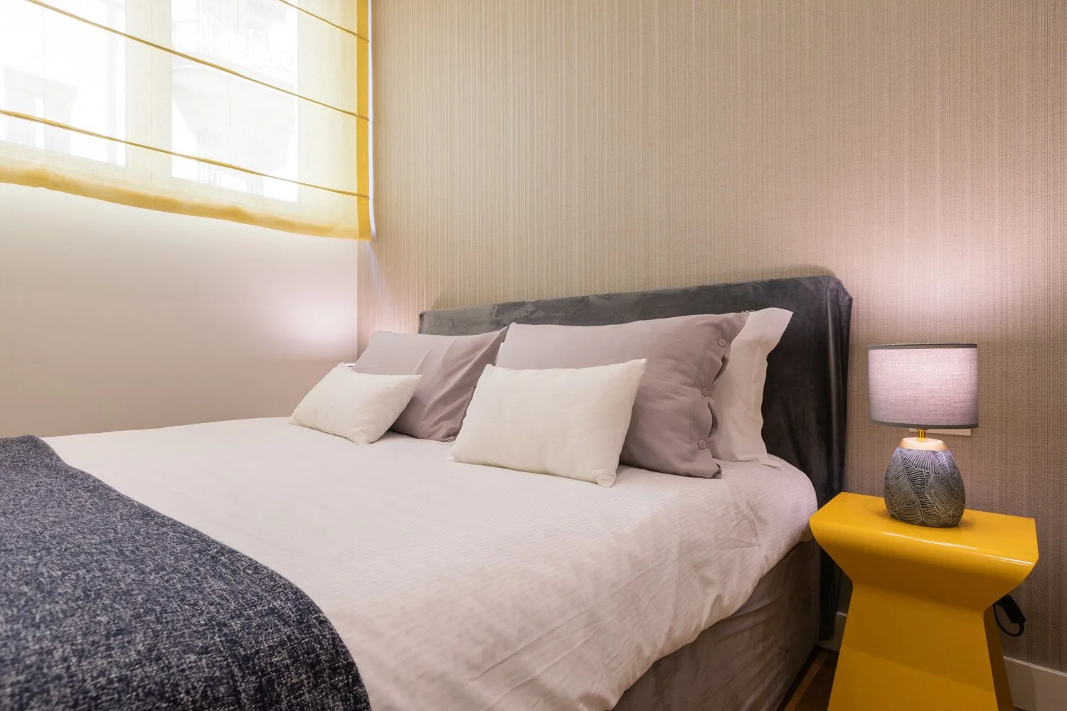 Un dormitorio con una cama tendida y una mesita de noche.