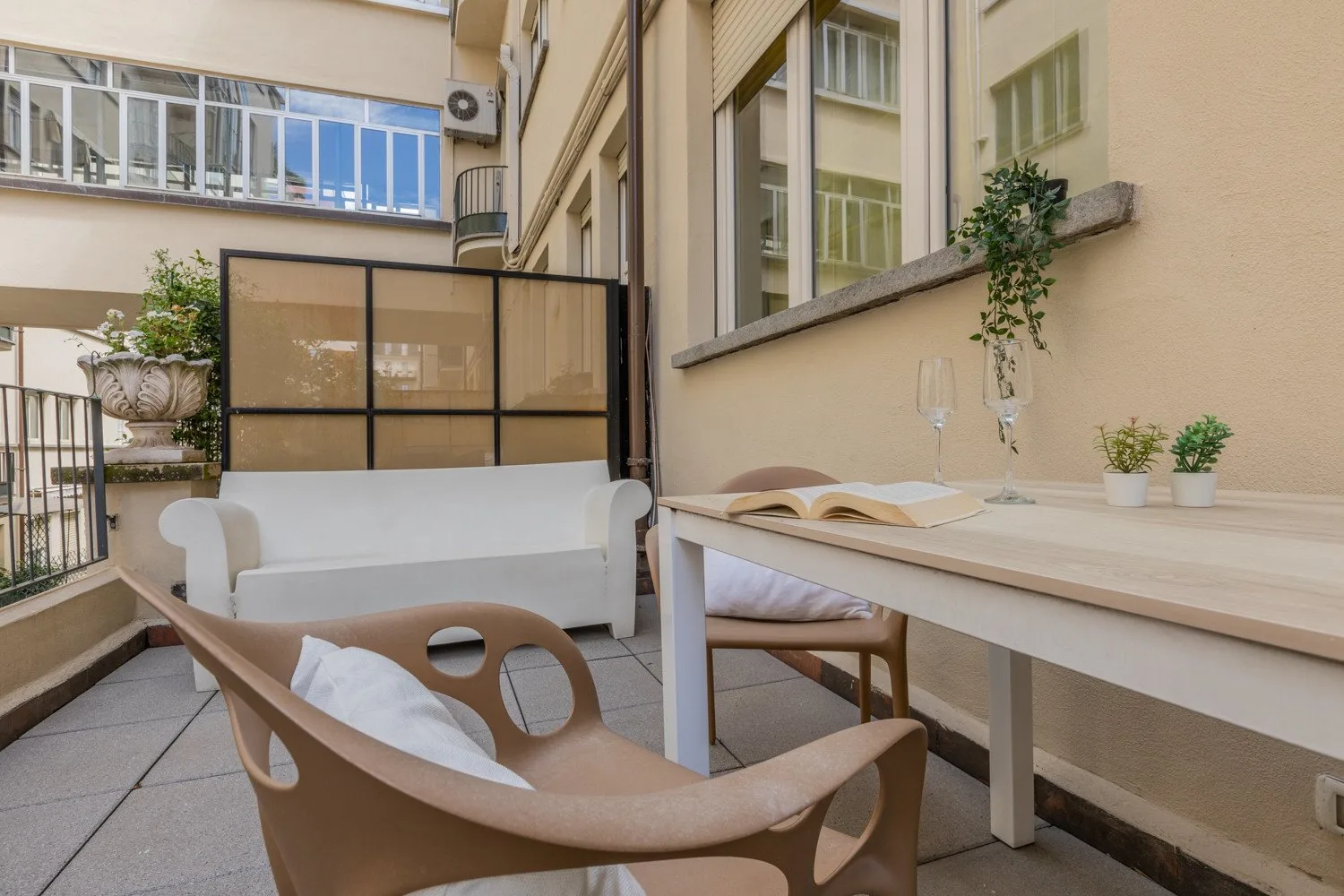 Una pequeña zona de estar al aire libre con sillas, una mesa y plantas en macetas.