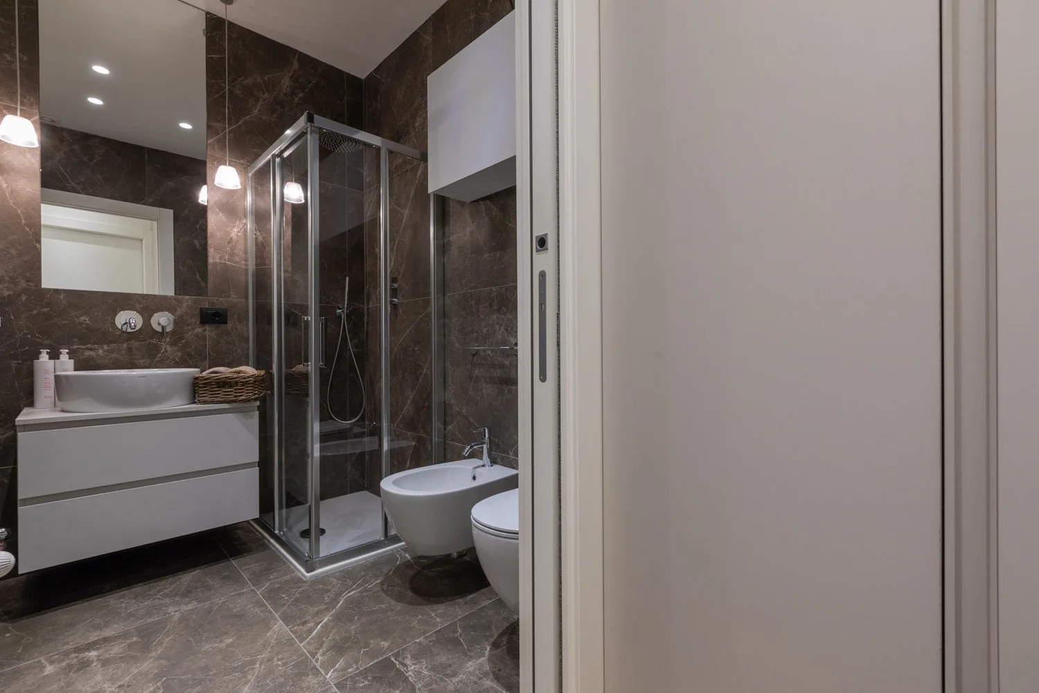 Un baño con ducha de vidrio, tocador e inodoro.