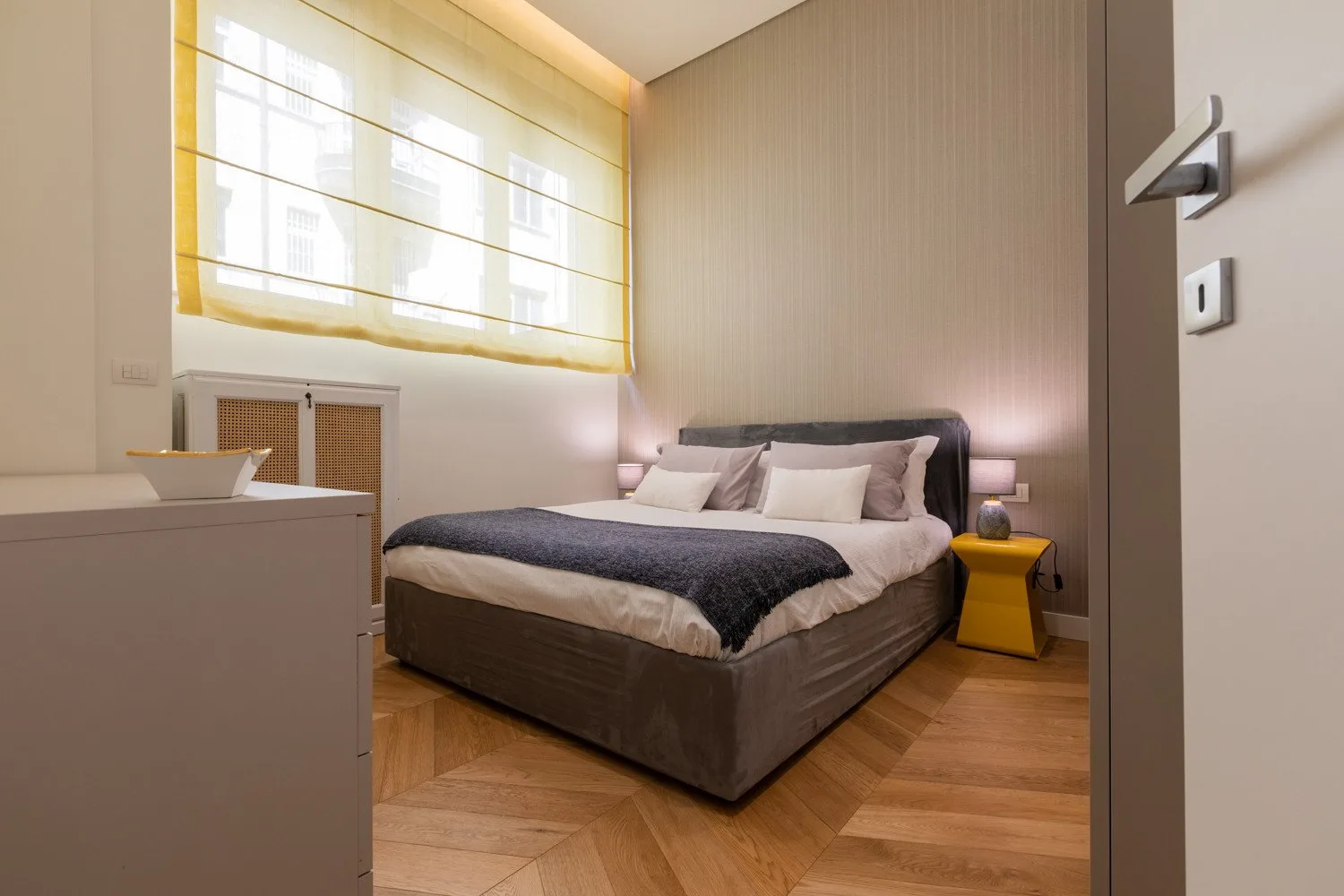 Un dormitorio con una cama grande bajo una ventana luminosa.