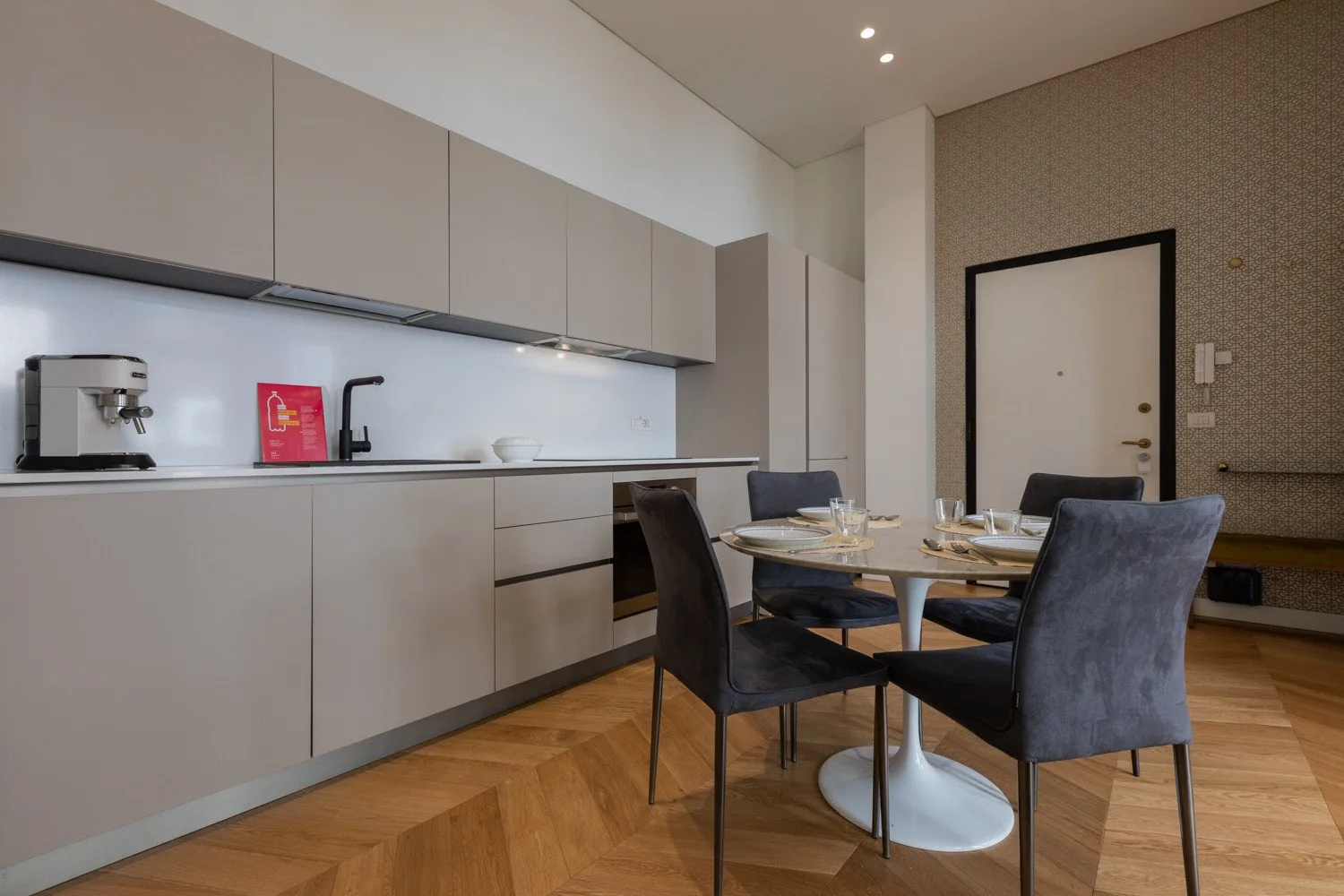 Comedor con una mesa y asientos junto a una cocina moderna.
