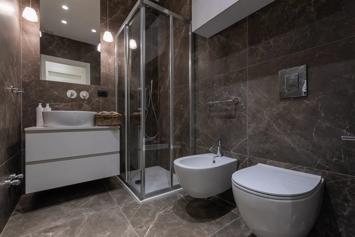 Un baño alicatado con ducha, lavabo e inodoro.