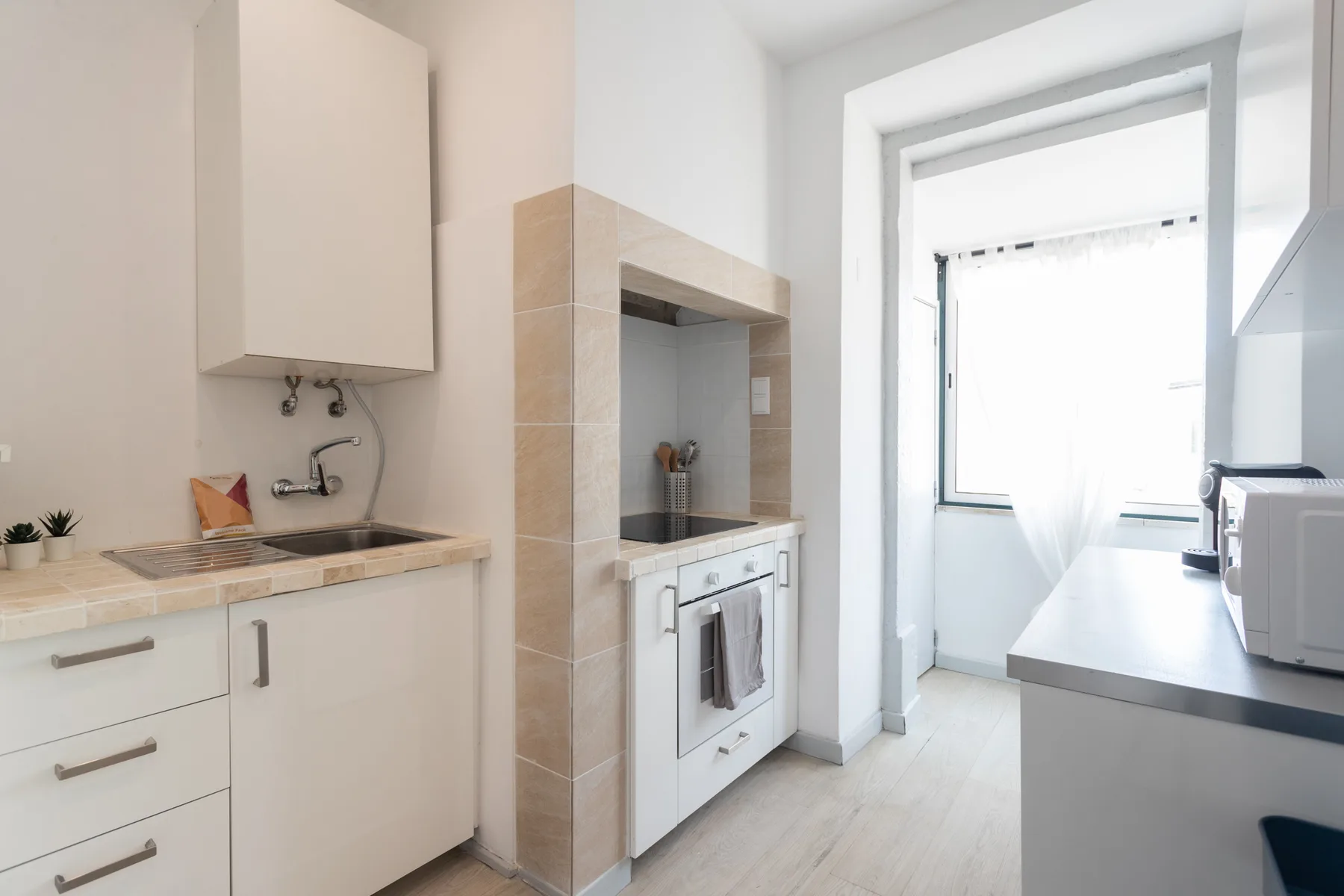 A bright kitchen with countertops, a sink, and a window.
