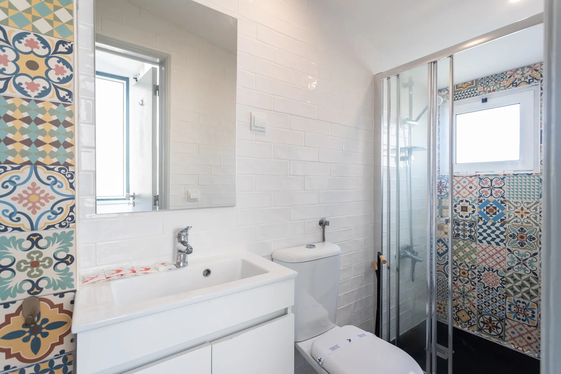 A bright tiled bathroom with a bathtub, sink, and glass shower.