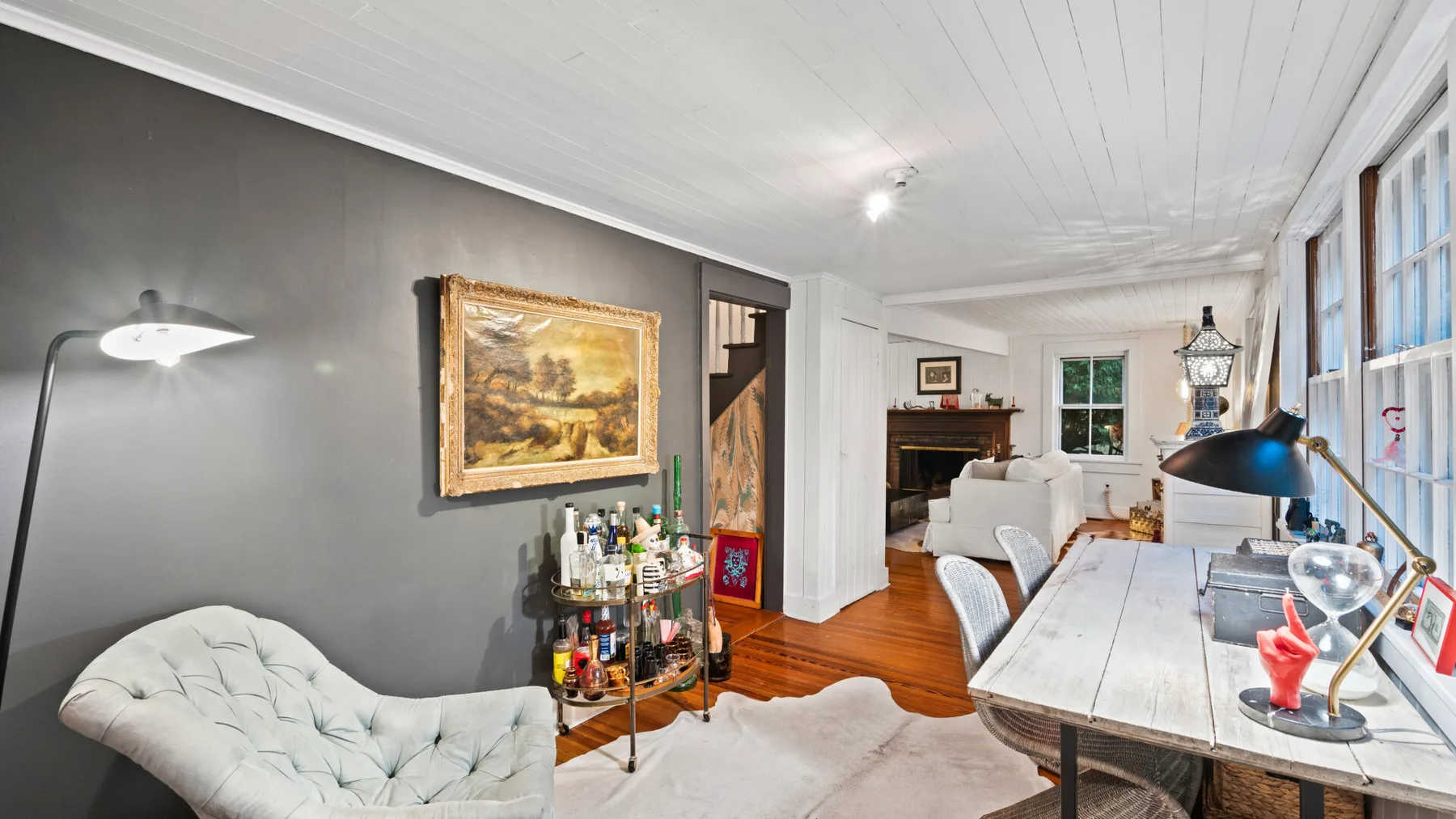 A living room with a white table beside a gray wall and framed artwork.