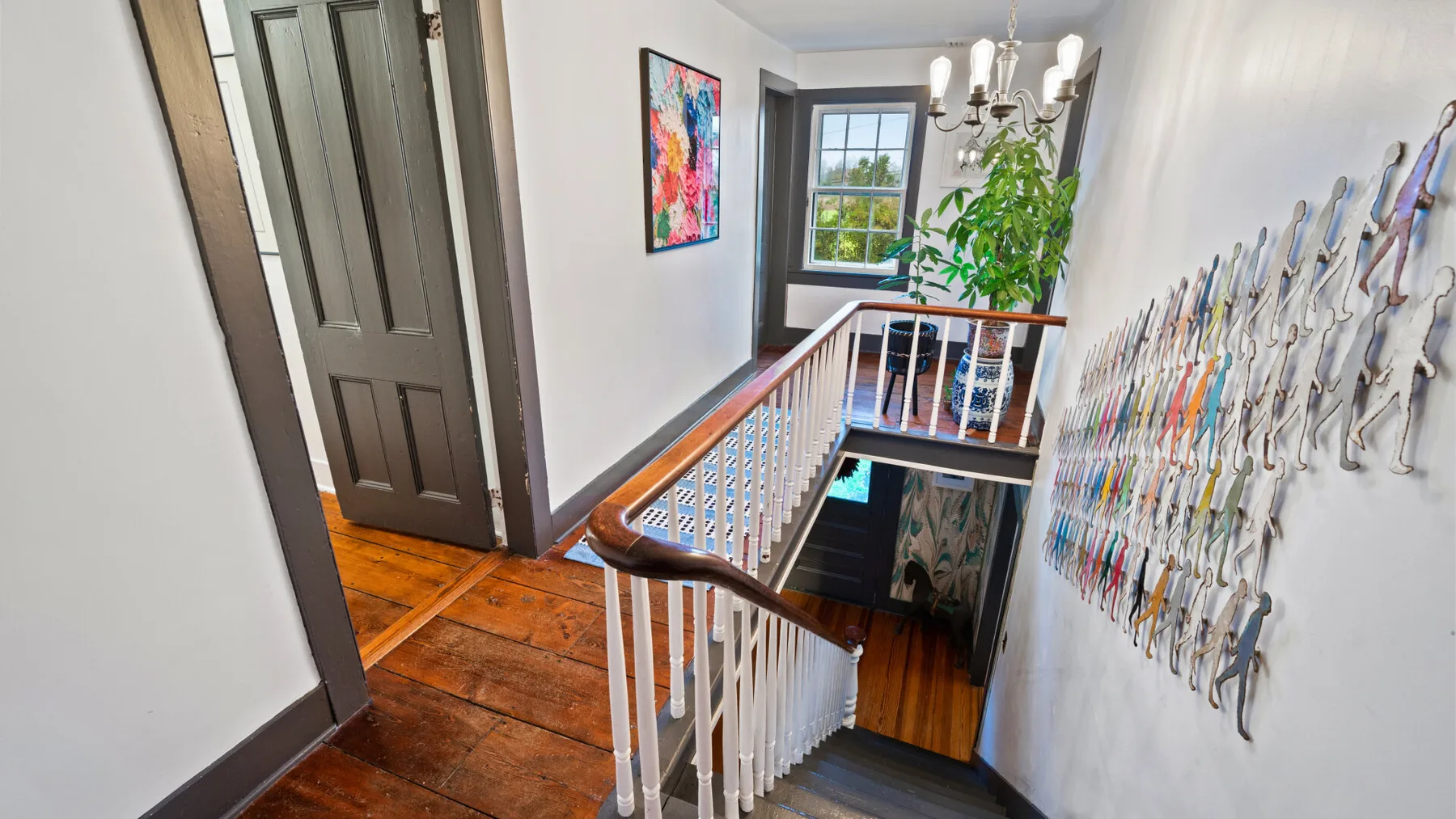 A stair landing with a wooden railing, artwork, and a window.