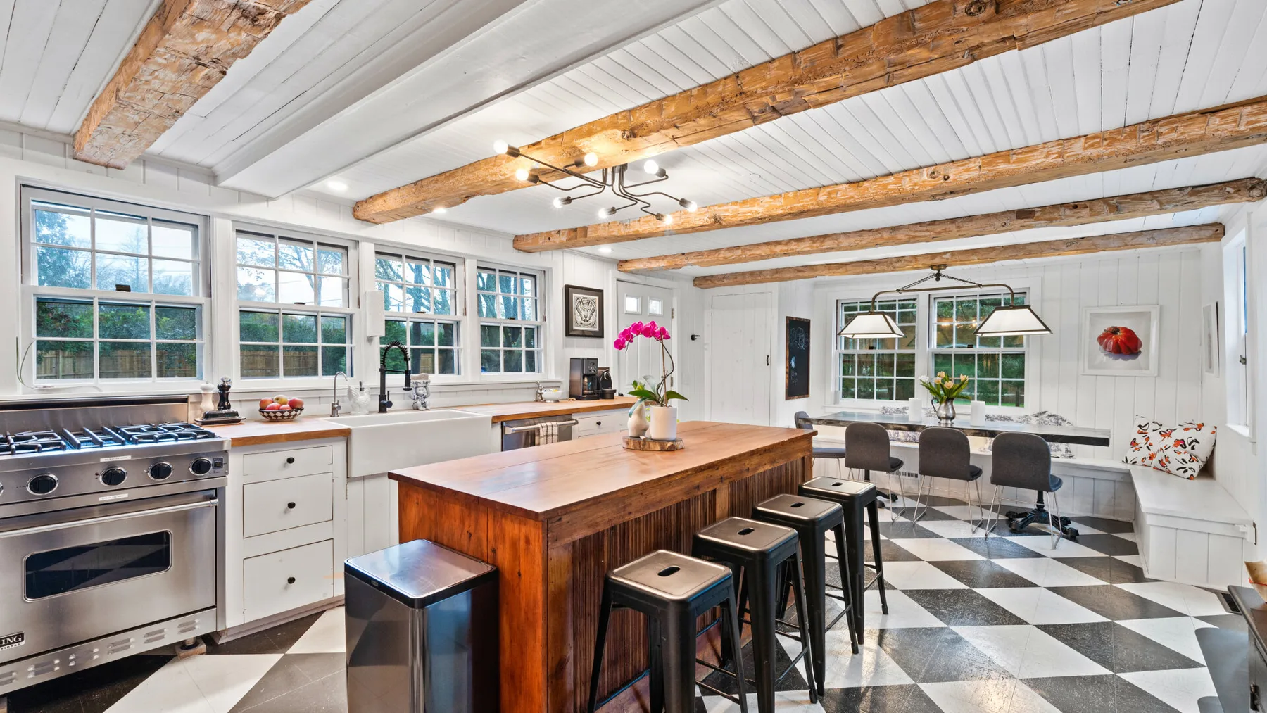 A bright kitchen with a large wooden island and a black-and-white tiled floor.