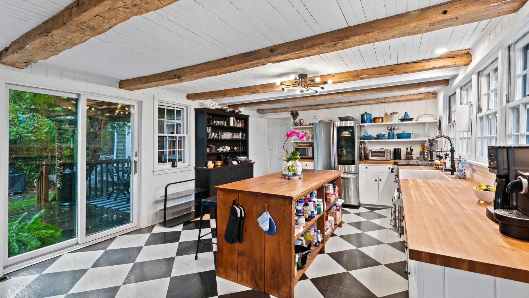 A bright kitchen with a central island, open shelving, and large windows.
