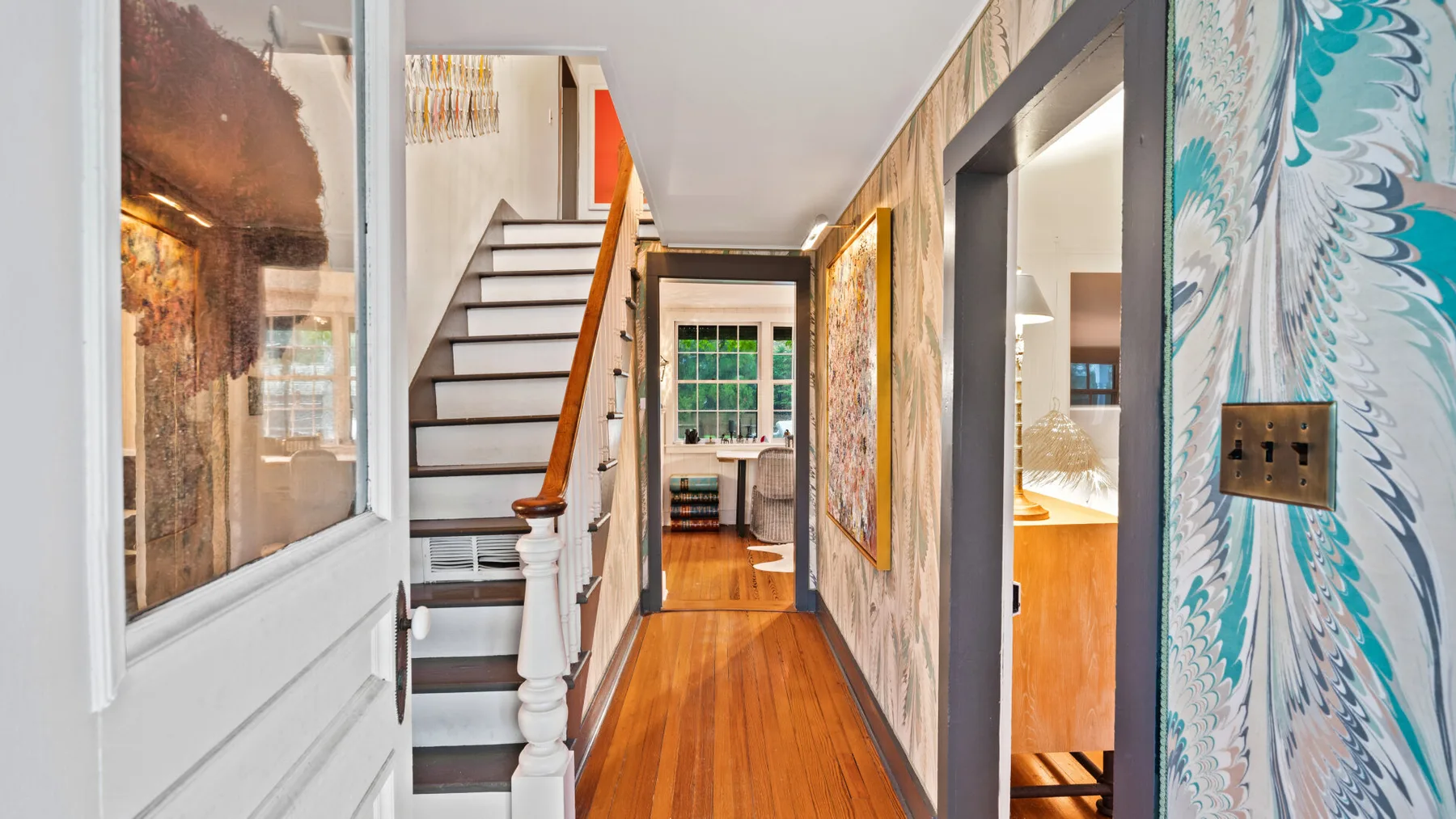 A narrow hallway with a staircase and several open doorways.