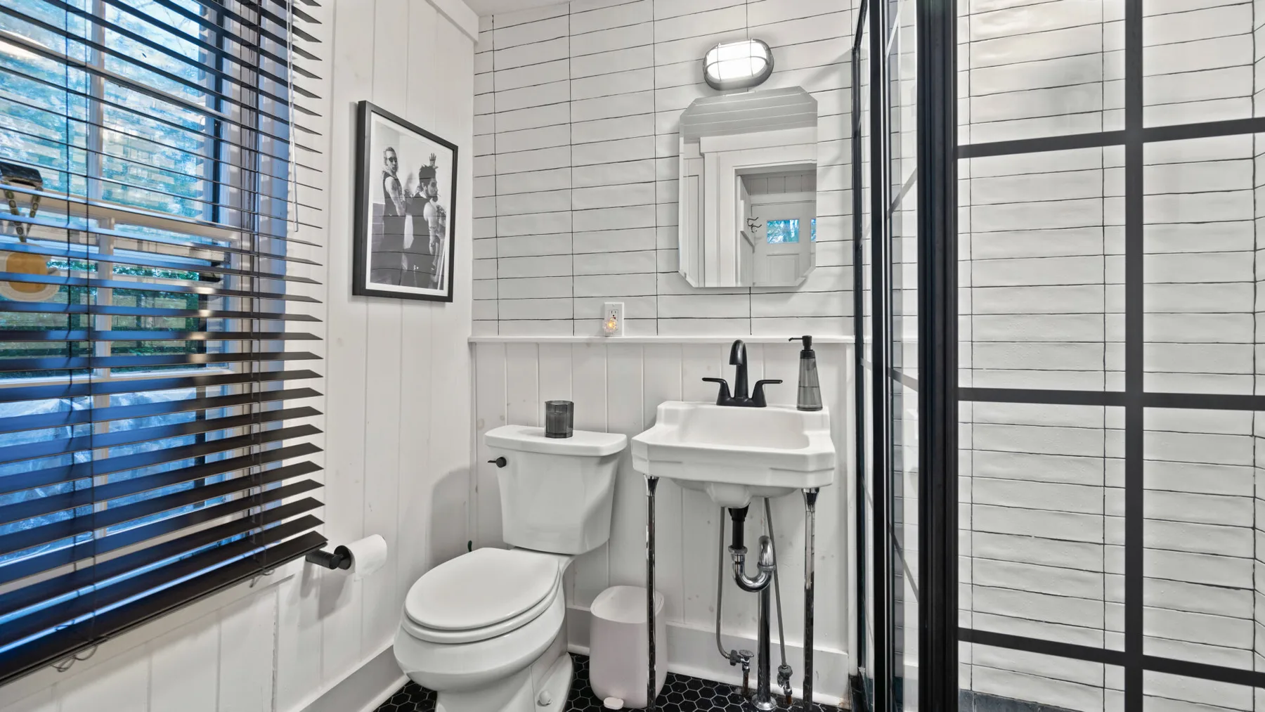 A bathroom with a toilet and a sink beside a window with blinds.