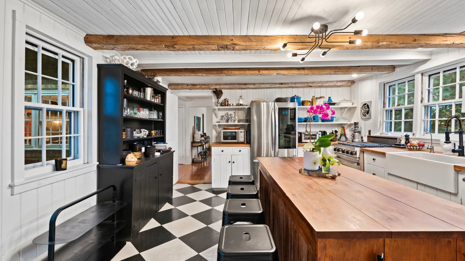 A bright kitchen with a long island, dark stools, and large windows.