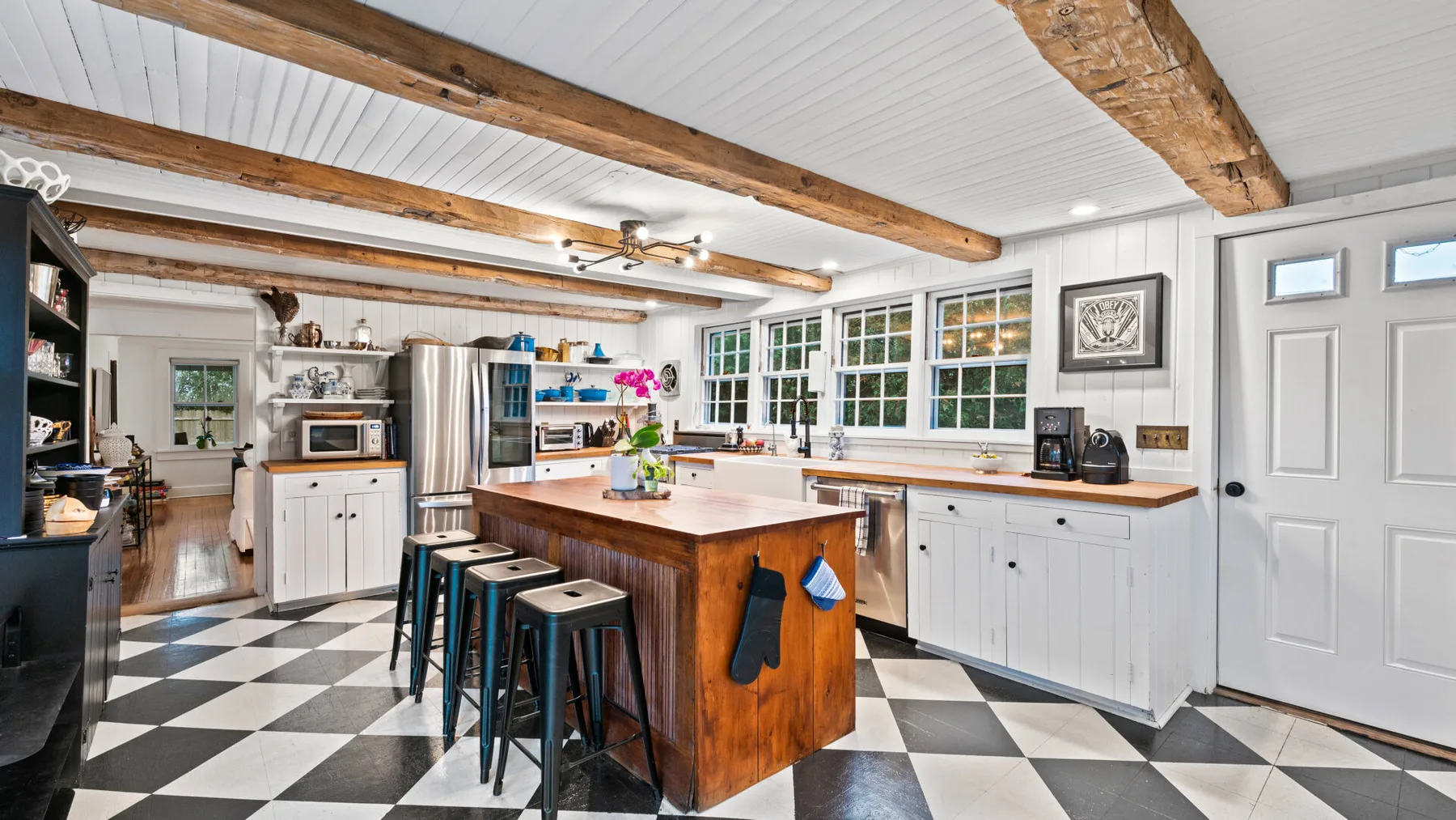A bright kitchen with a central island, white cabinetry, and a black-and-white checkered floor.