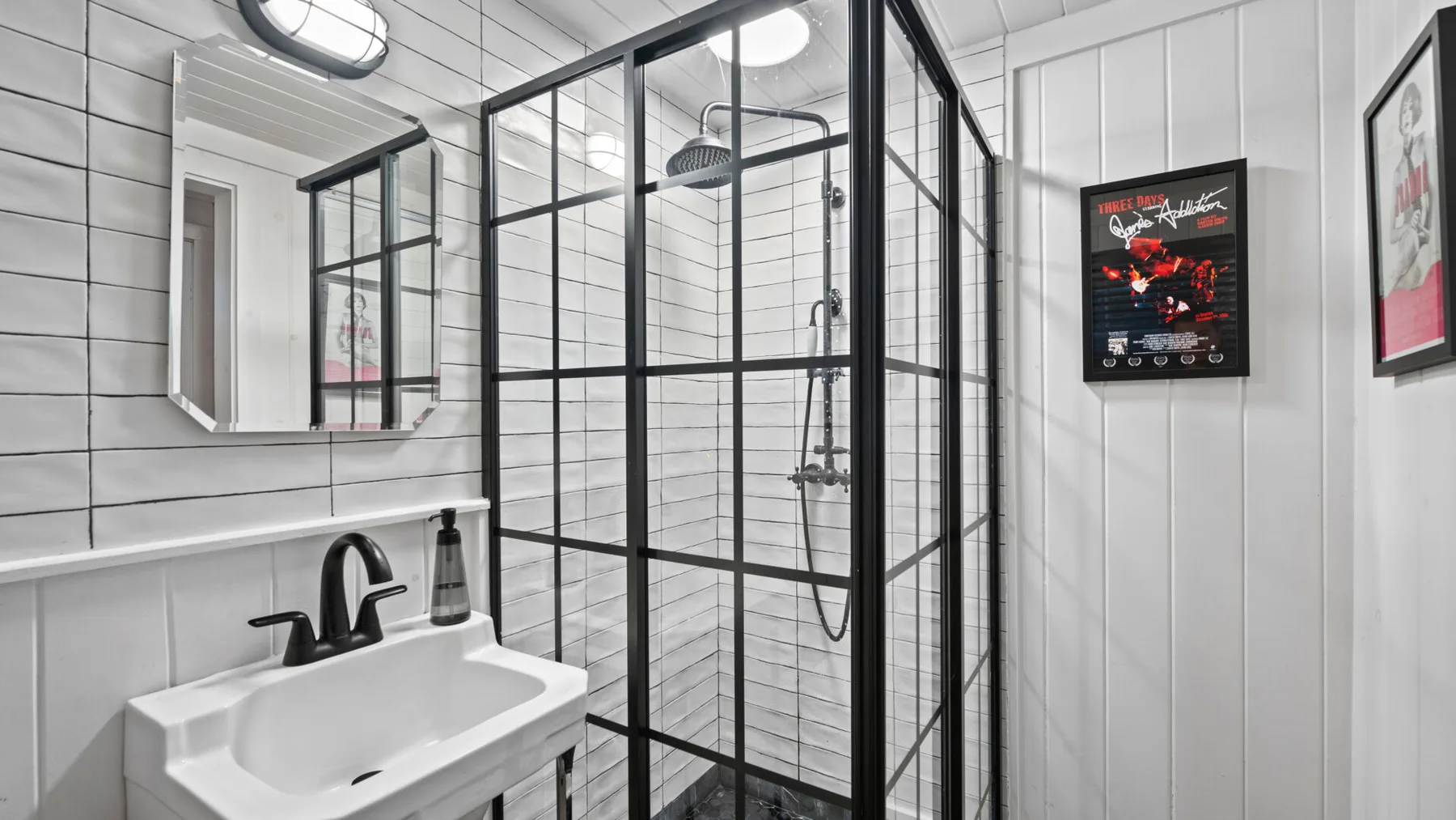 A tiled bathroom with a wall-mounted sink and glass shower enclosure.