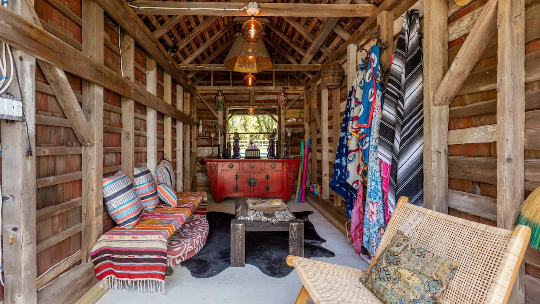 A rustic wooden room with a colorful daybed and patterned textiles.