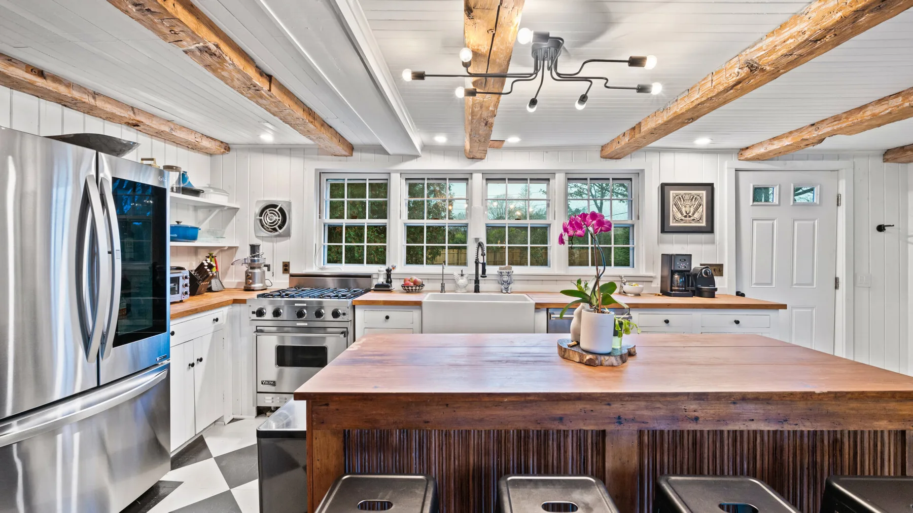A bright kitchen with a large wooden island and stainless steel appliances.