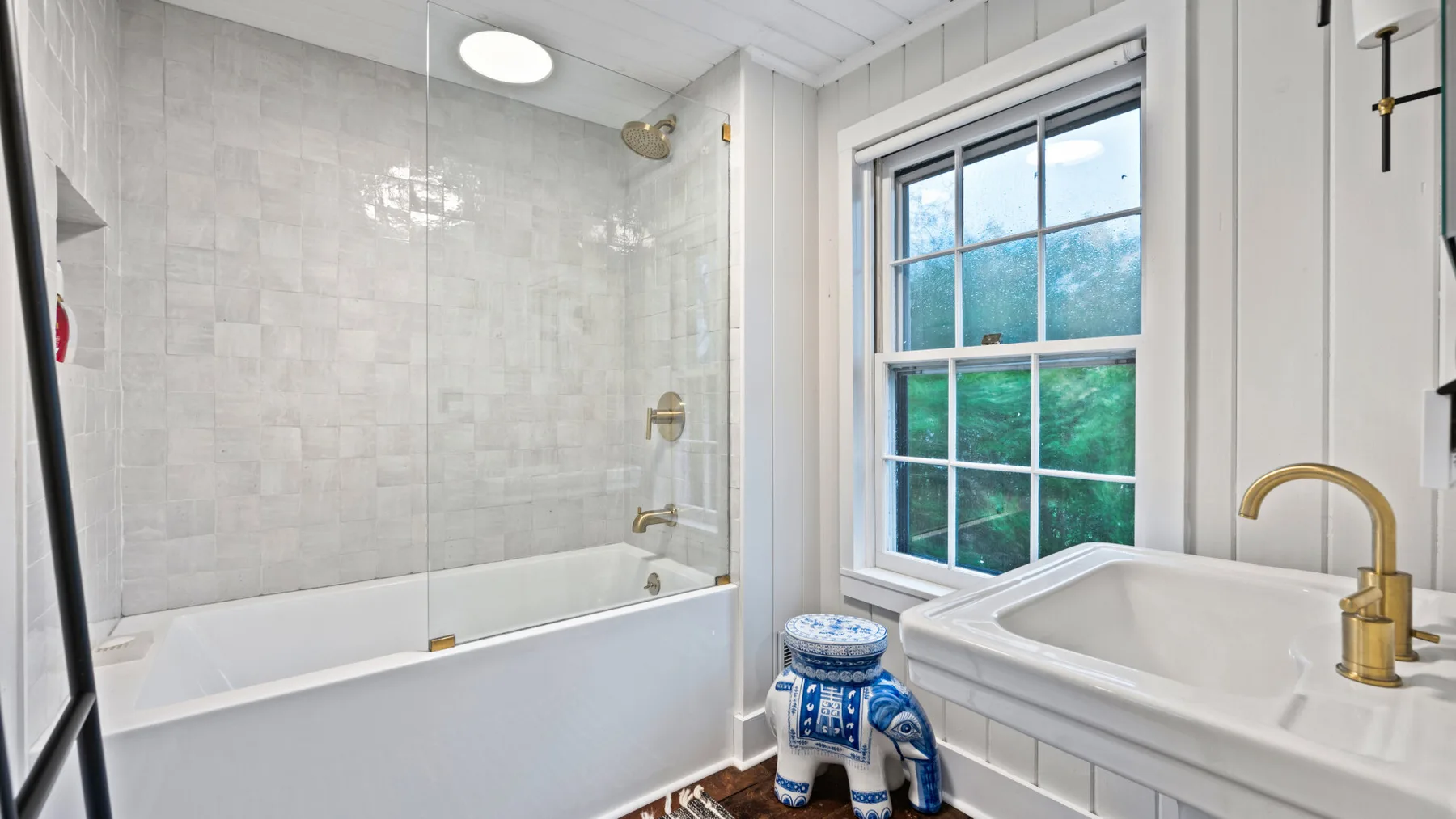 A bathroom with a bathtub and a separate sink beside a window.