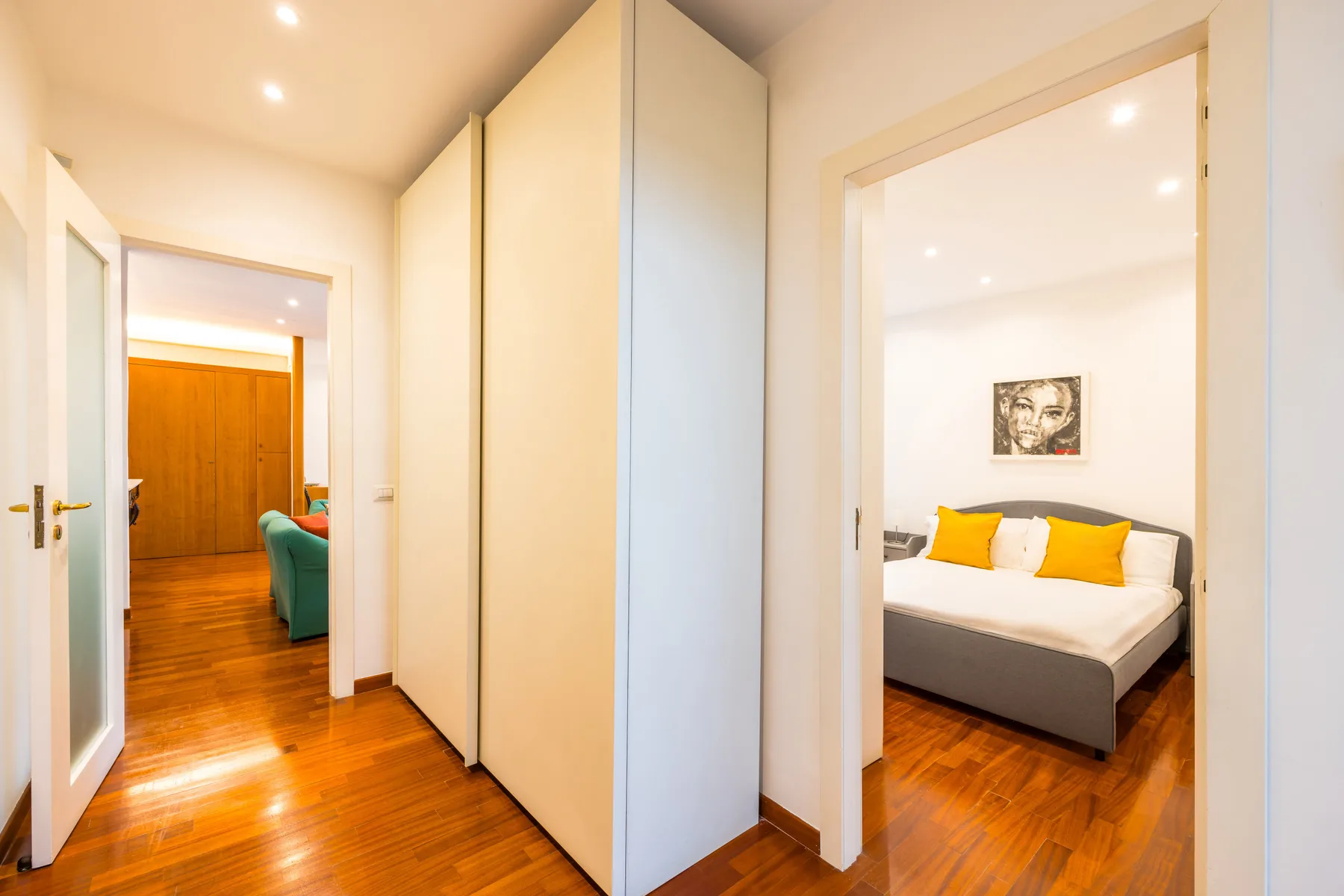 A bright hallway with doorways opening onto a bedroom and a living area.
