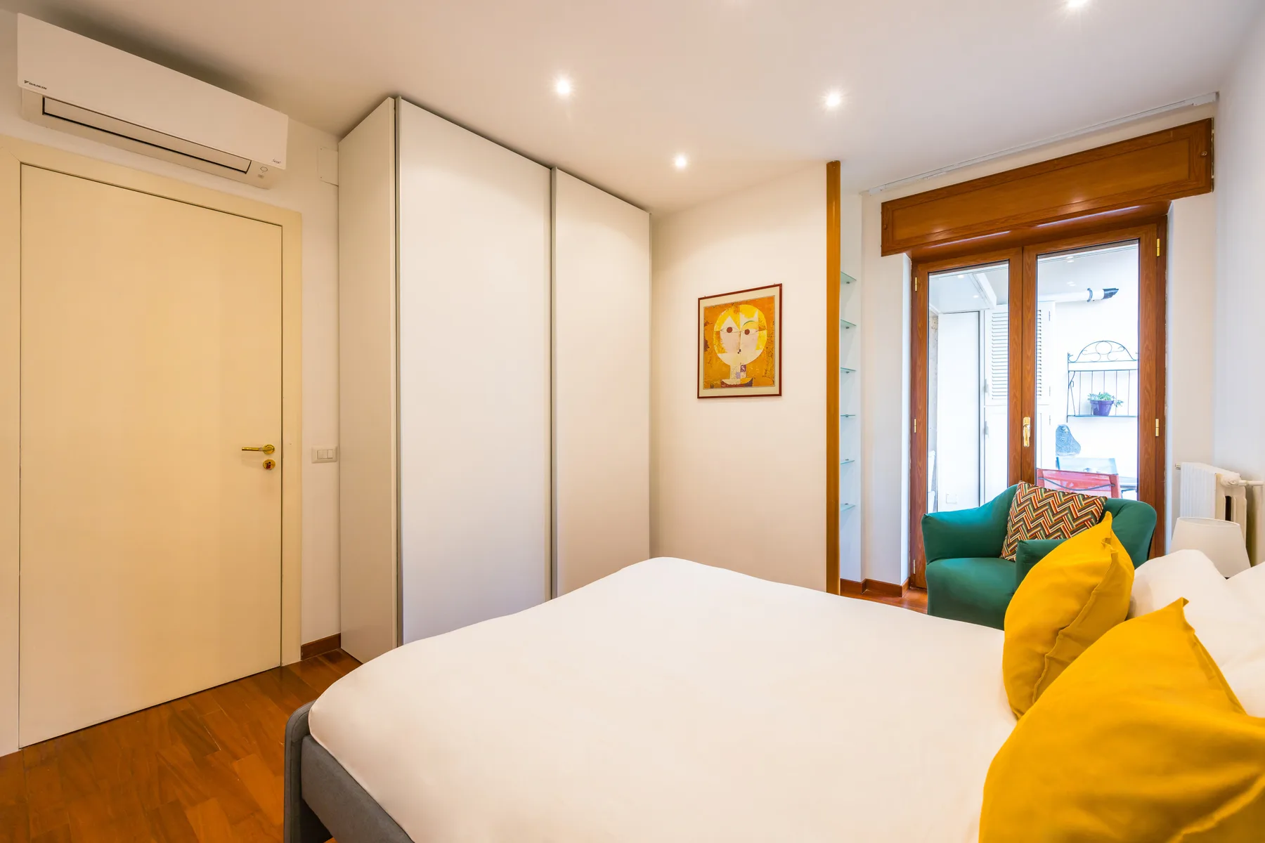 A bedroom with a bed, colorful cushions, and a window.