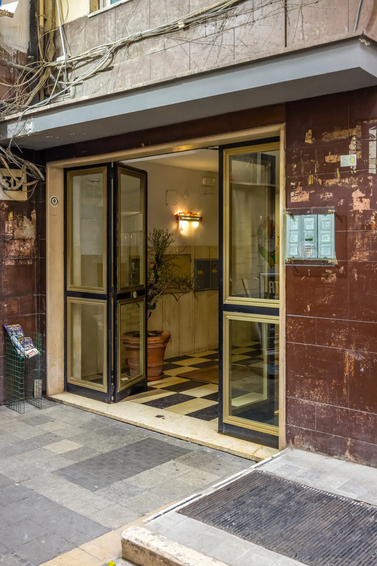 An open building entrance with glass doors and a tiled floor.
