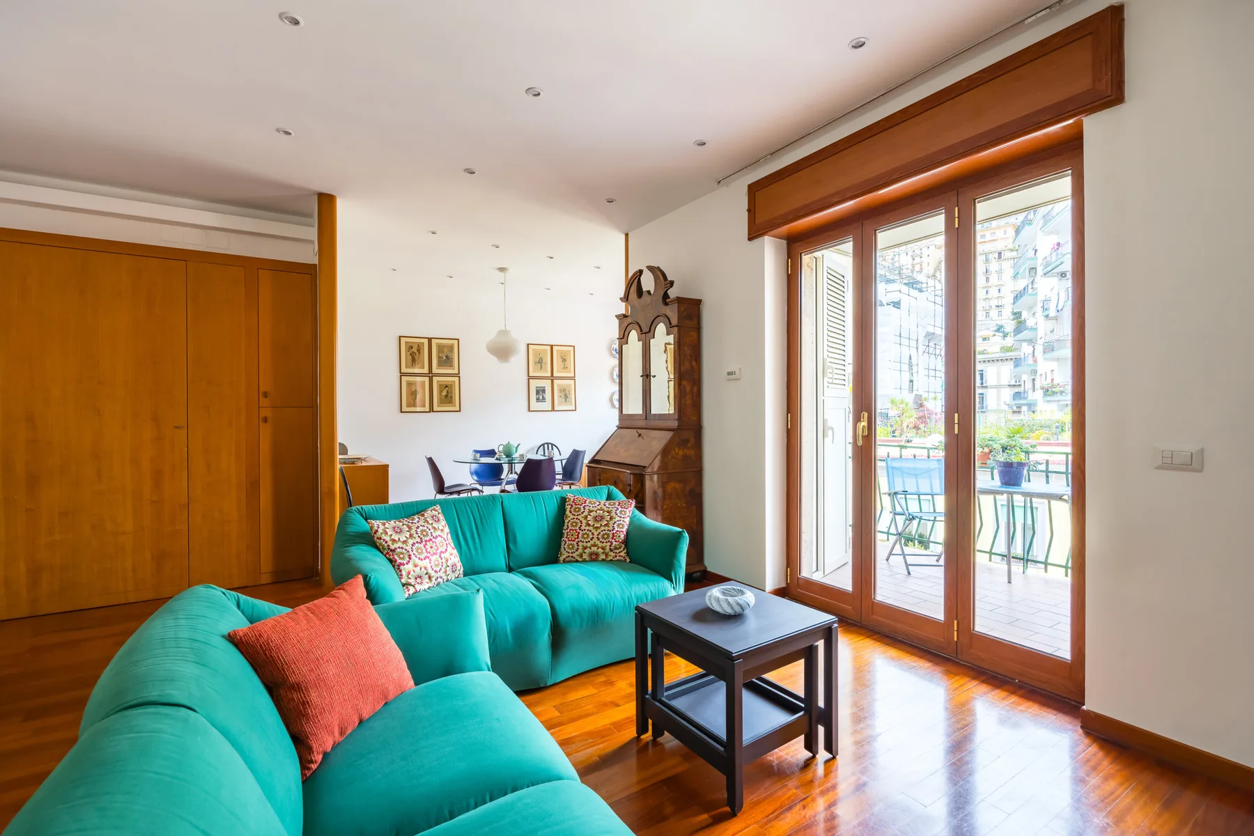 A living room with turquoise seating and large glass doors opening onto a balcony.