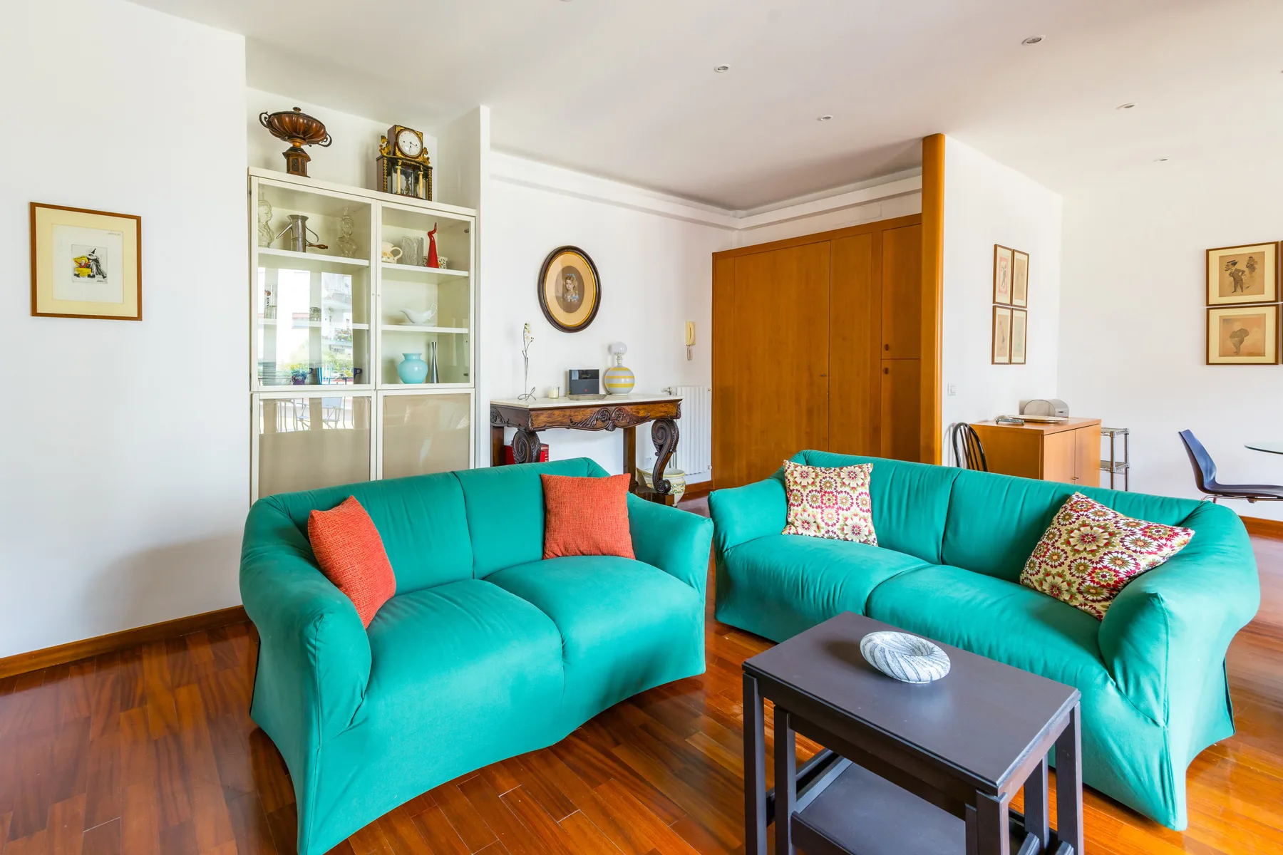 A bright living room with teal seating and a dark coffee table.