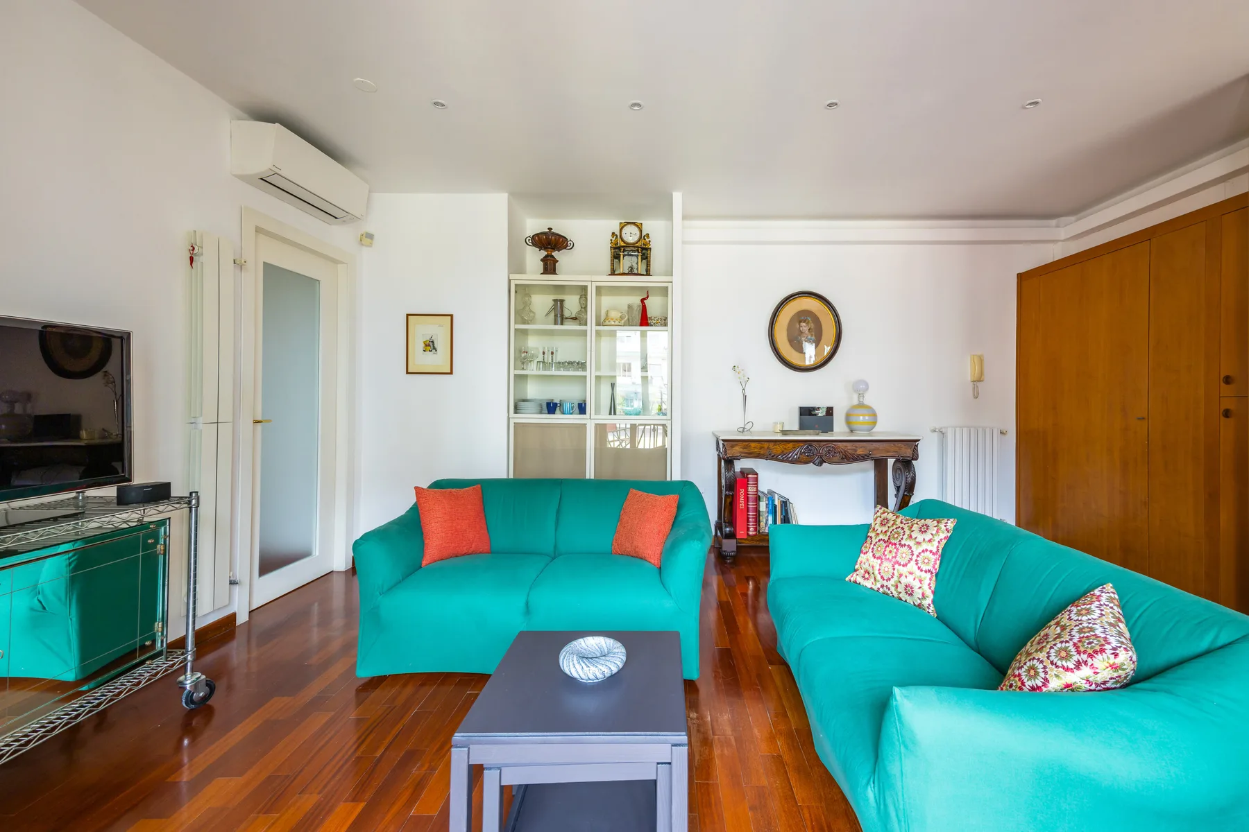 A bright living room with turquoise seating, a coffee table, and built-in shelving.