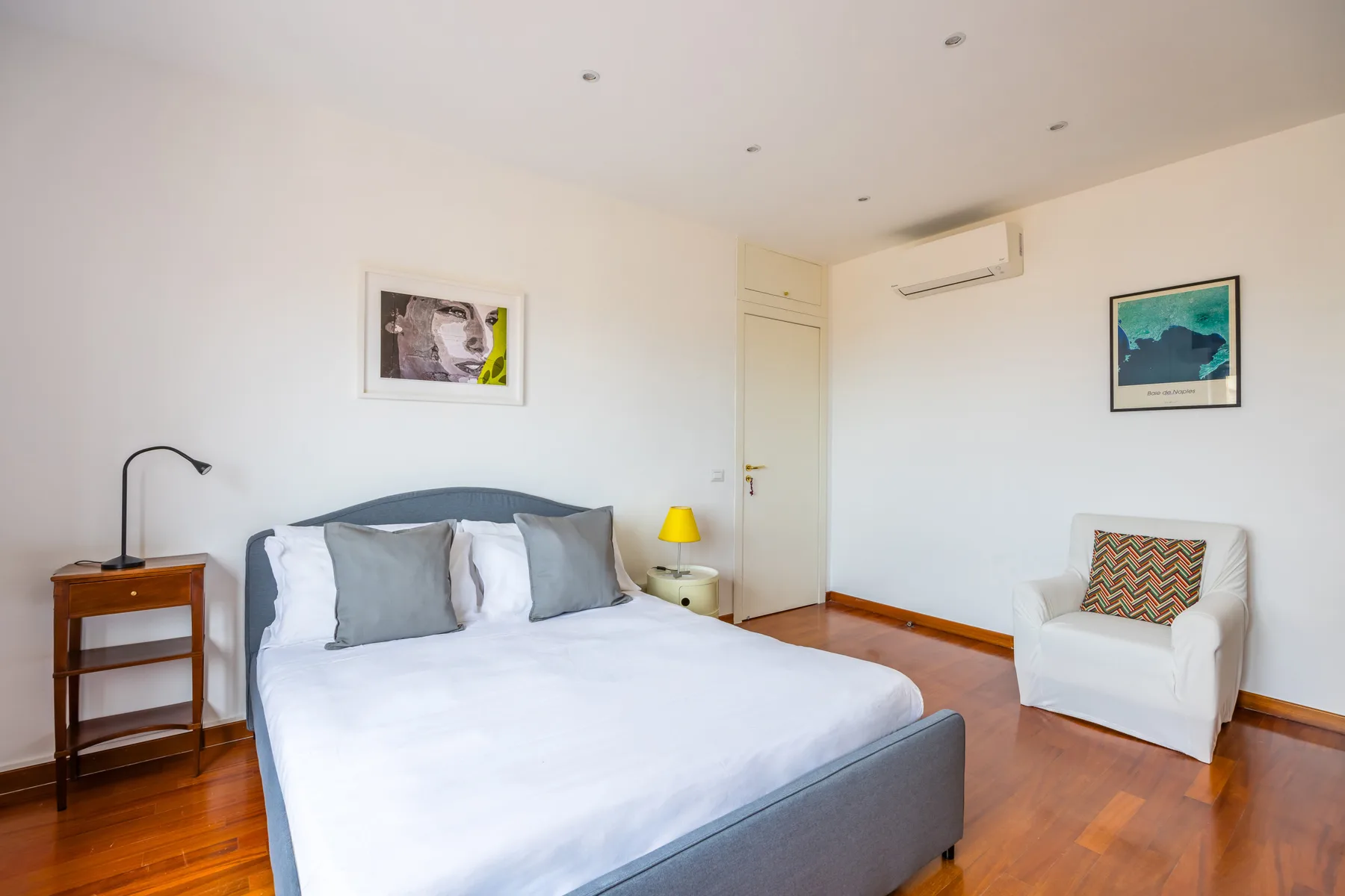 A bedroom with a bed, bedside table, and an armchair.