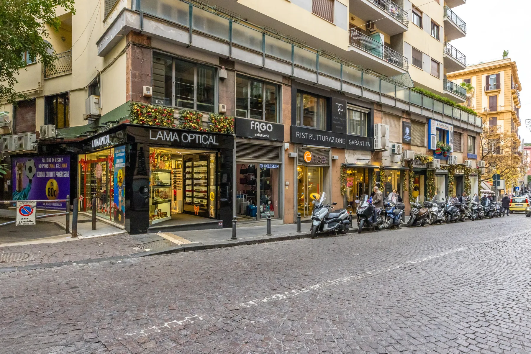 A street corner lined with storefronts and parked scooters.
