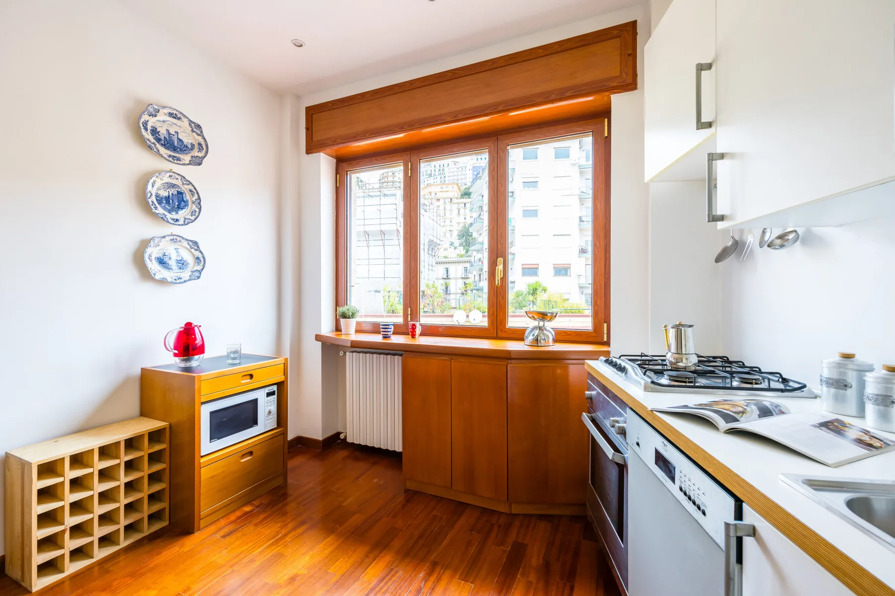A bright kitchen with wooden cabinetry and a wide window above the counter.