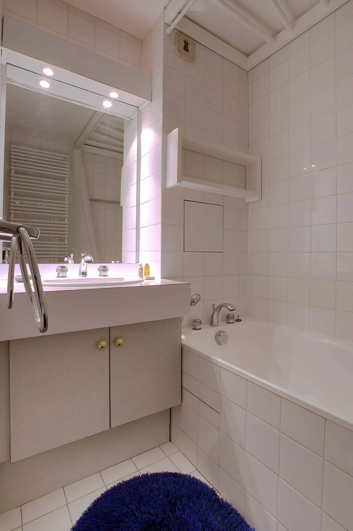 A tiled bathroom with a bathtub, vanity, and large mirror.