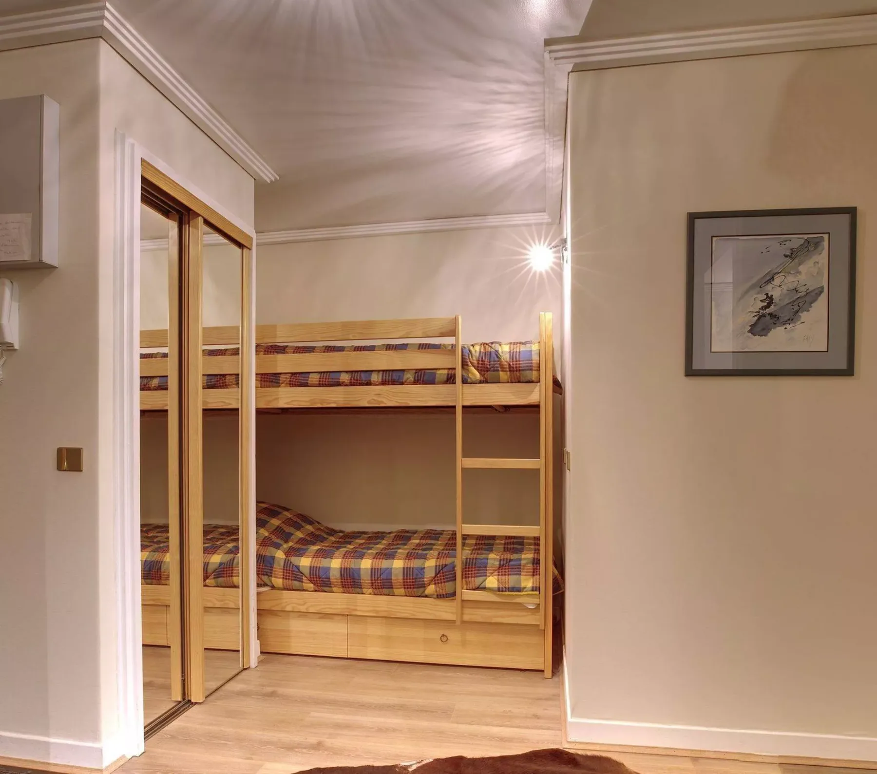 A bunk bed with patterned bedding is set in a compact bedroom.