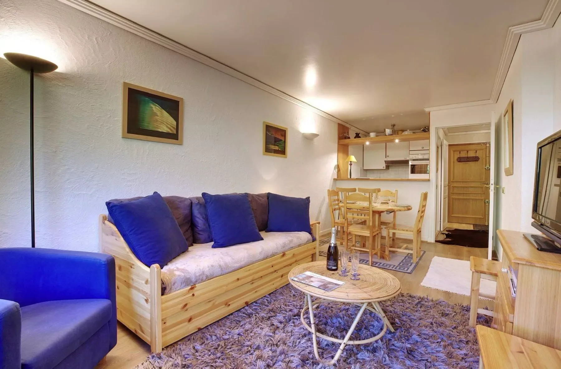 A living room with a wooden sofa, a coffee table, and a dining area.